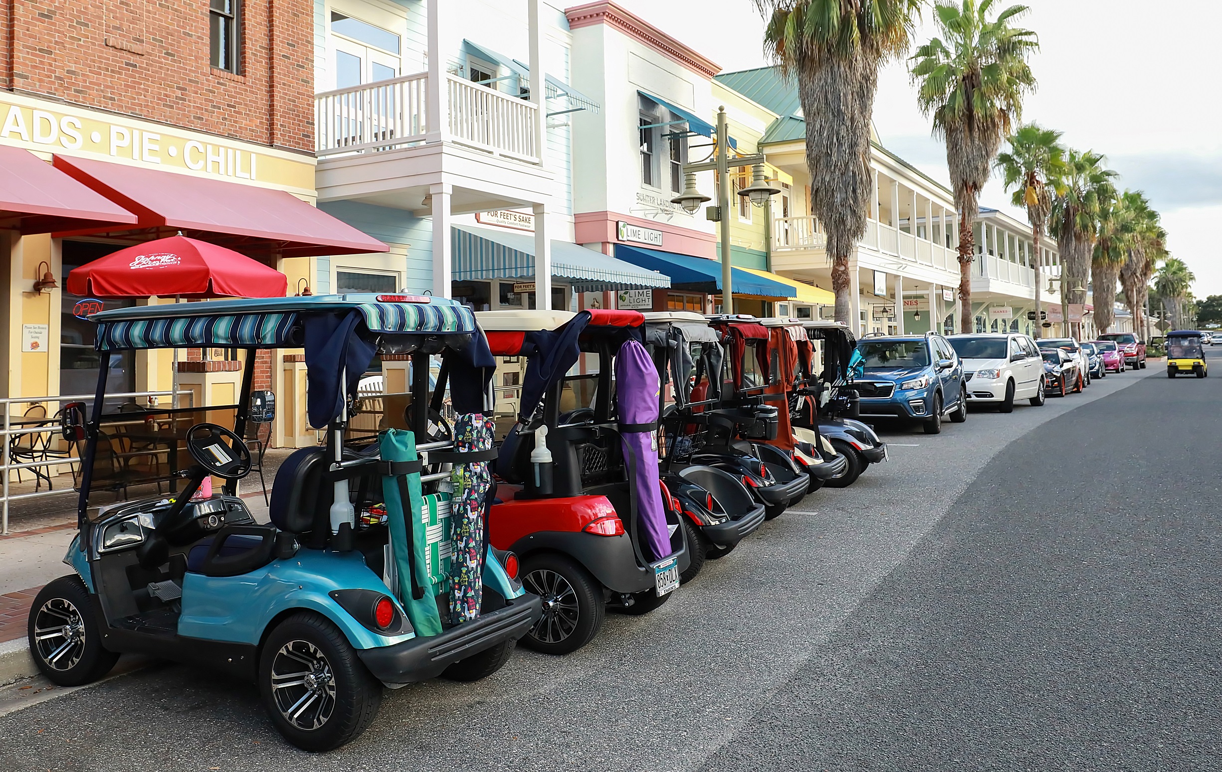 The Villages, Florida, USA - October 24, 2020: Golf carts parked downtown at Market Square in Sumpter Landing. The Villages is a popular retirement golf cart loving community.